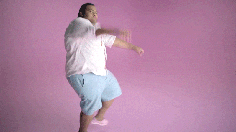 This guy confidently does some stylish dance moves on a pink background