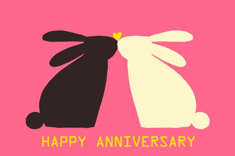 A black bunny kissing a white bunny with a Happy Anniversary at the bottom