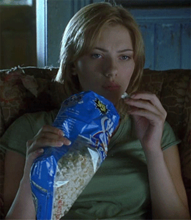 A young Scarlett Johanson sits on the couch eating popcorn