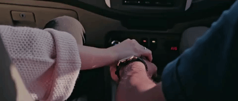 This couple hold hands while in the car
