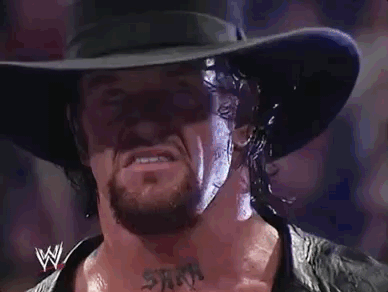 Undertaker in the middle of the ring with his famous white-eyed pose